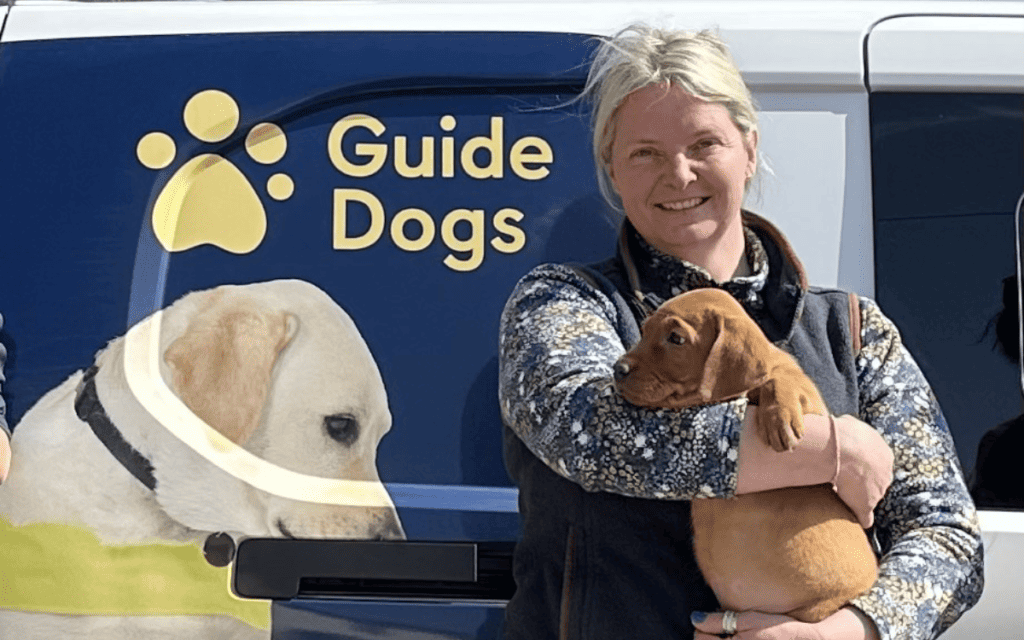 Dog breeder Rebecca Walters holding red fox labrador - a guide dog puppy